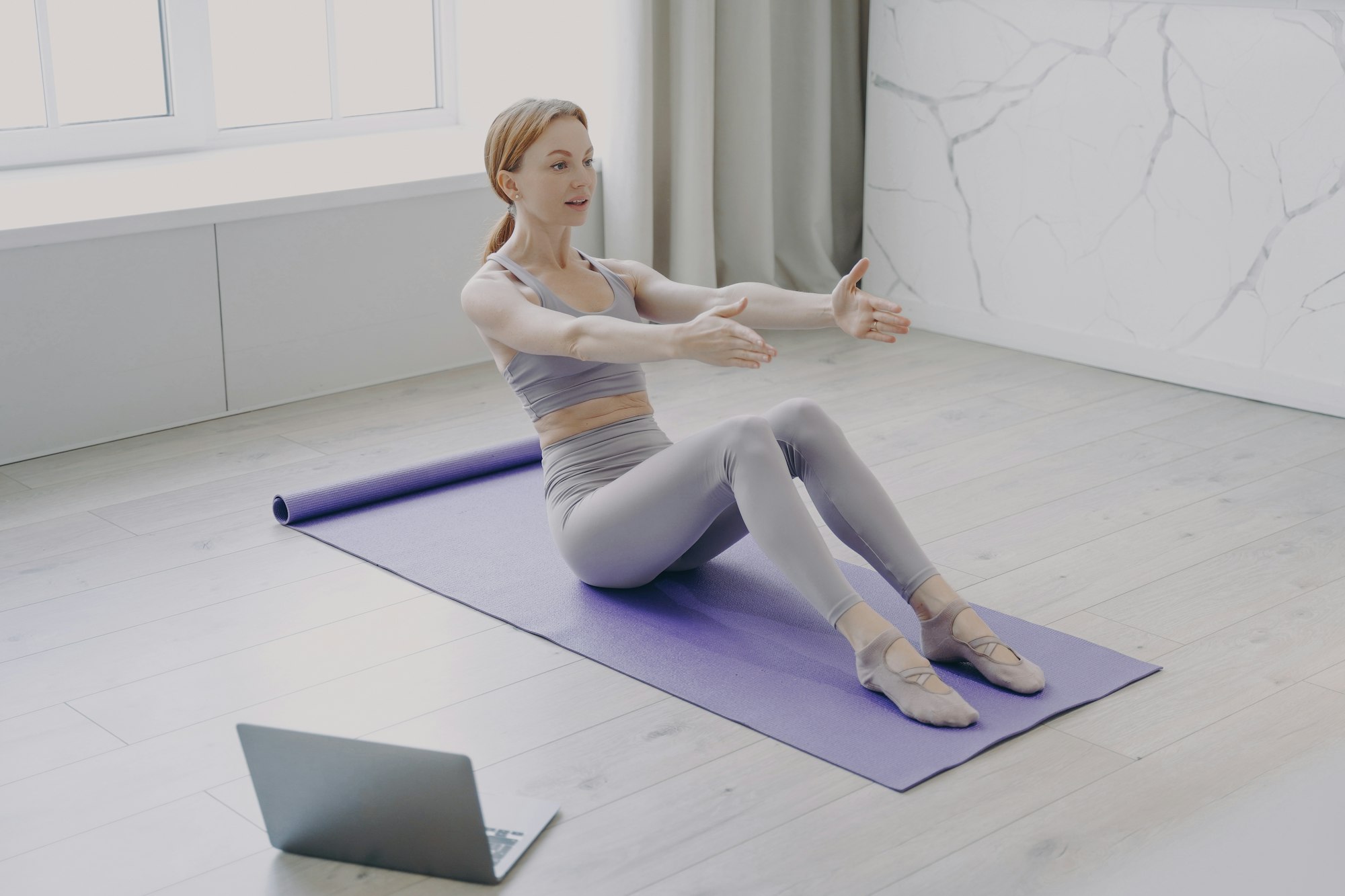 Press exercise and pilates at home. Video lessons on laptop. Concept of distance fitness classes.